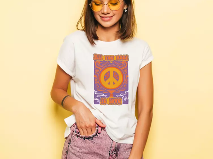 Young woman wearing a peace shirt on a yellow background